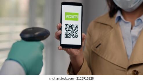 Cropped Shot Of Woman In Mask Holding Smartphone With Vaccinated Qr Code For Scanning In Modern Office Building Or Hospital