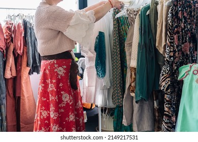 Cropped Shot Of Woman Picking Up And Buying Clothes In A Fashion Shop. Concept Of Shopping.