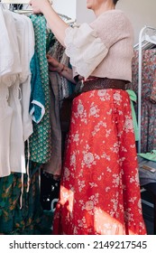 Cropped Shot Of Woman Picking Up And Buying Clothes In A Fashion Shop. Concept Of Shopping.