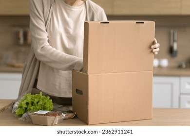 Cropped shot of woman producing packed fresh vegetables from cardboard box, receiving parcel from supermarket customer logistic service, opening paper container, preparing dinner - Powered by Shutterstock