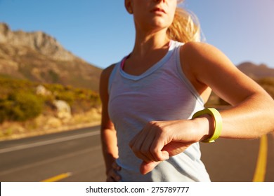 Cropped shot of woman running and checking her sports watch