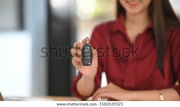 Cropped\
shot woman sale car with showing key to\
customer.