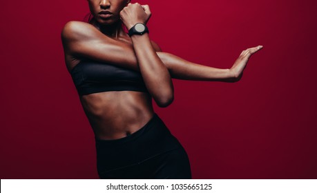 Cropped Shot Of Woman Stretching Her Arms. Female Doing Warmup Stretching Workout On Red Background.