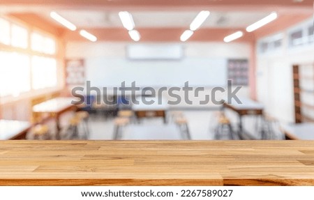 Cropped shot of wooden table with books, stationery and copy space in blurred study room.Empty classroom or presentation room interior with desks, chairs and whiteboard