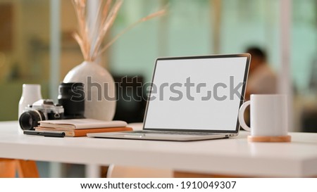 Cropped shot of worktable with laptop, cup, stationery and camera in office room, clipping path