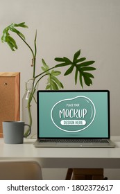 Cropped Shot Of Worktable With Mock Up Laptop, Mug, Plant Vase And Notice Board In Home Office Room 