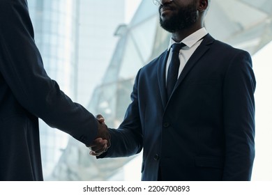 Cropped Shot Of Young African American Businessman In Dark Blue Suit Handshaking With New Business Partner After Negotiating