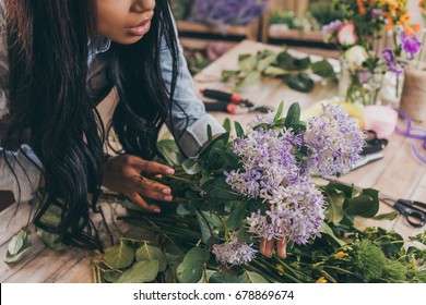 cropped shot of young african american woman arranging flowers and green leaves in flower shop - Powered by Shutterstock