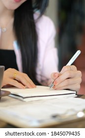 Cropped shot of young business woman writing information on notebook at her workspace.