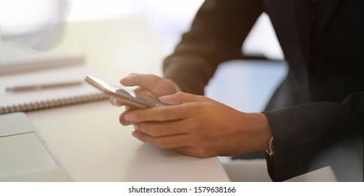 Cropped shot of young businesswoman holding smartphone in her office room  - Shutterstock ID 1579638166