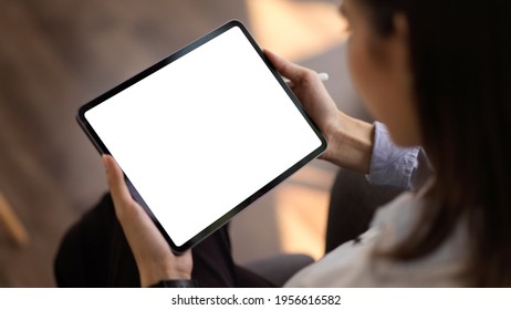 Cropped shot of young businesswoman looking at mock up tablet in office room, clipping path  - Powered by Shutterstock