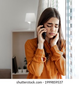 Cropped Shot Of A Young Businesswoman Looking Stressed Using A Smartphone And Standing Near A Window. Receiving Unwanted Phone Calls. Alone Thoughtful Sadness Woman Using A Smartphone At Home.