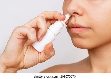 Cropped shot of a young caucasian woman using nasal spray for a runny nose and congestion isolated on a white background. Treatment of the disease. Rhinitis, sinusitis, cold. Dependence on drops