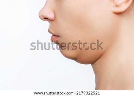 Cropped shot of a young caucasian woman's face with double chin isolated on a white background. Overweight, flabby and sagging skin. Profile
