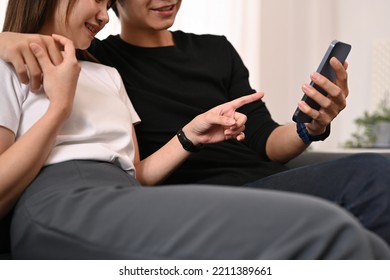 Cropped Shot Of Young Couple Embracing And Shopping Online On Internet Via Smart Phone. People And Technology Concept