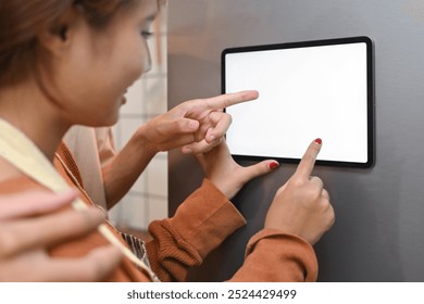 Cropped shot of young couple interacting with digital tablet mounted on the door of a refrigerator - Powered by Shutterstock