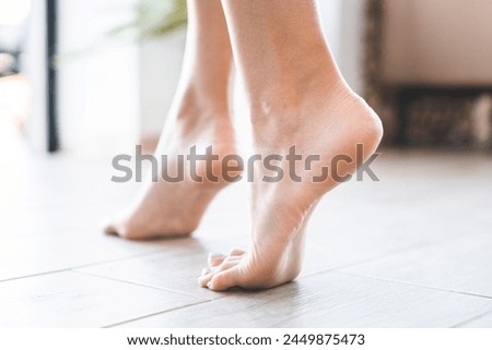 Cropped shot of young female feet stepping on the floor indoors in house. Foot fetish concept. Healthy soles, nail and toes skin care. Heated floor at home
