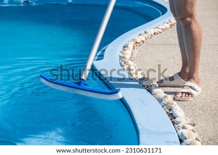 Cropped shot of young housekeeping using a pool brush for cleaning swimming pool.