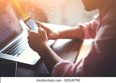 Cropped shot of a young man downloading in mobile store popular applications and multimedia programs. Man's hands using device at co-working office. Blurred background and infographics icons effect