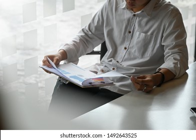 Cropped Shot Young Man Reading Business Report On Office Table.