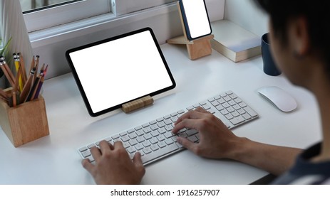 Cropped shot of young man typing on wireless keyboard and working with digital tablet. - Powered by Shutterstock