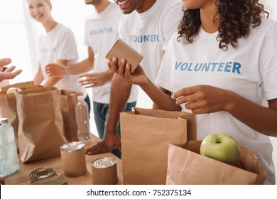 cropped shot of young volunteers group packing food and drinks for charity - Shutterstock ID 752375134