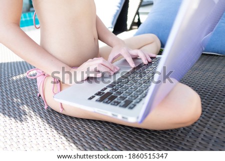 Cropped shot of  young woman in bikini sitting on a laptop
