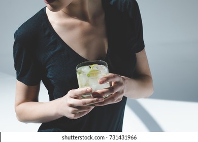 Cropped Shot Of Young Woman Holding Glass With Gin Tonic, Lime And Ice Cubes