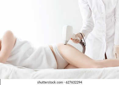 Cropped shot of young woman lying and receiving laser skin care on hip