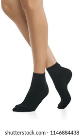 Cropped side view of beautiful female legs in black socks, isolated against a white background. The young woman walking on her tip-toes. Comfortable legwear for ladies and girls. Cozy women's hosiery.