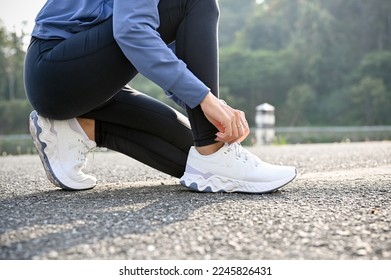 cropped and side view image, A woman in sportswear tying her running shoes, preparing to run on the street. Active healthy lifestyle concept - Powered by Shutterstock