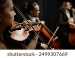 Cropped side view shot of unrecognizable female musician playing violin with chamber quartet on stage, focus on string instrument and bow