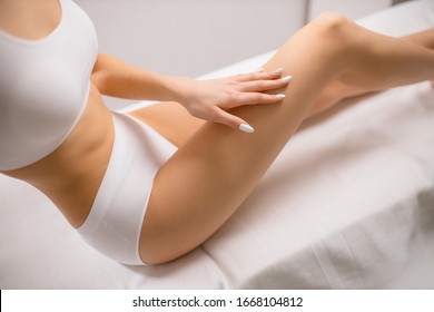 cropped smoothy legs of slim female, woman after laser epilation in beauty salon. woman touch legs. skin and body care, hairless, hygiene concept