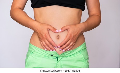 A Cropped Studio Shot Of A Woman Holding Her Heart-shaped Hands On Her Fat Stomach. The Concept Of Body Positivity, Love Your Body.