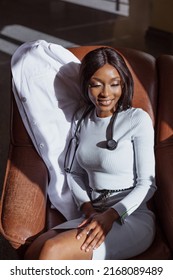 cropped sunny image of Young female black medical worker put off her uniform resting sitting in armchair in the clinic hall. Concept of racial diversity in health care. Minority in medical system