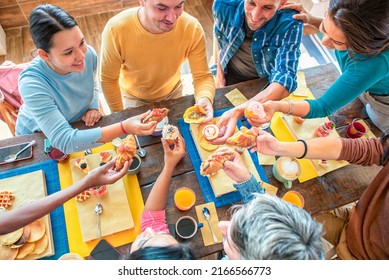 Cropped Top Of Multiethnic Large Group Of Friends At Cafe Table Restaurant Eating Muffin And Cakes. Diverse People Celerating Sweet Breakfast Together Enjoying Happy Holiday. Lifestyle And Joy Concept