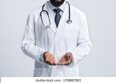 Cropped of unrecognizable black doctor in white with open palms, giving something invisible, white background - Powered by Shutterstock