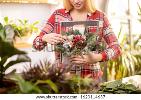 cropped unrecognizable florist woman with blonde hair holding wonderful composition of plants, wearing red casual shirt