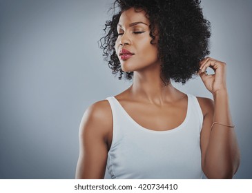 Cropped upper body view of beautiful young African woman looking sideways with closed eyes and fingers touching hair and copy space