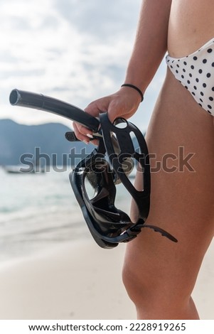 Cropped vertical shot of unrecognizable woman holding snorkeling kit on the shore of the beach.