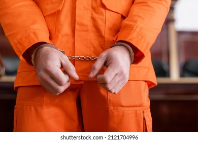 Cropped View Of Accused Man In Handcuffs And Orange Jail Uniform In Court