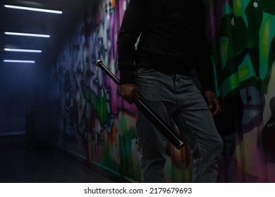 Cropped view of african american bandit holding baseball bat near graffiti on wall in garage