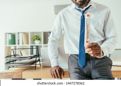 Cropped View Of African American Businessman Holding Thermometer Showing High Temperature In Office