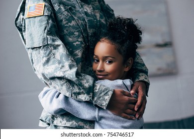 cropped view of african american daughter hugging soldier in military uniform at home