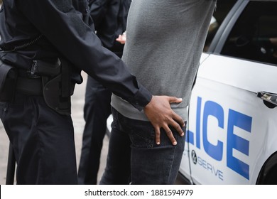 Cropped View Of African American Policeman Frisking Offender Near Patrol Car Outdoors