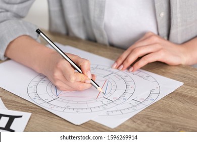 Cropped view of astrologer drawing natal chart on wooden table