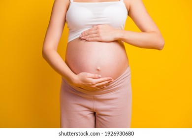 Cropped view of attractive pregnant girl touching large stomach parenthood preparation isolated over bright yellow color background