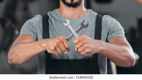 cropped view of auto mechanic holding two wrenches  - Shutterstock ID 1140445520