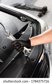 Cropped View Of Auto Mechanic In Latex Glove Holding Wrenches Near Open Hood