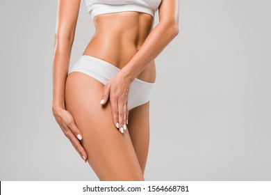 cropped view of beautiful slim woman in underwear touching leg isolated on grey - Shutterstock ID 1564668781